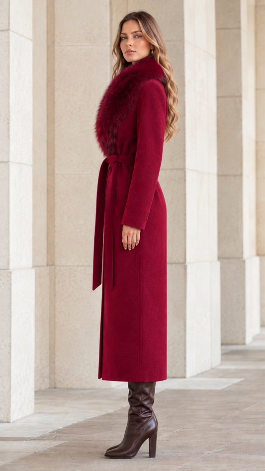 Side profile view of woman wearing burgundy long belted coat with faux fur trim