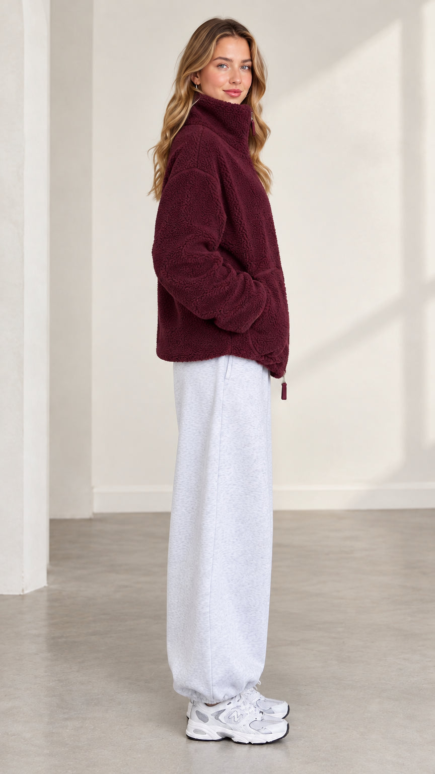 Side profile of model wearing burgundy plush fleece jacket with stand collar