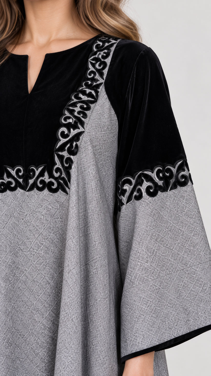 Close-up detail of black contrast panel with intricate scroll embroidery and notched neckline