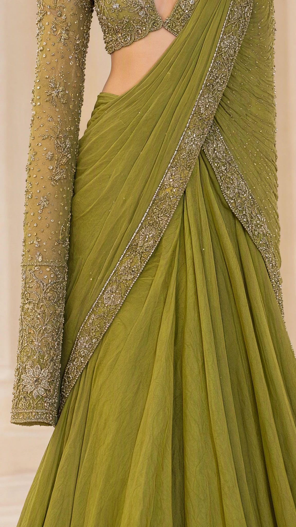 Close-up detail of embellished sleeve and draped pleated border on olive green saree gown