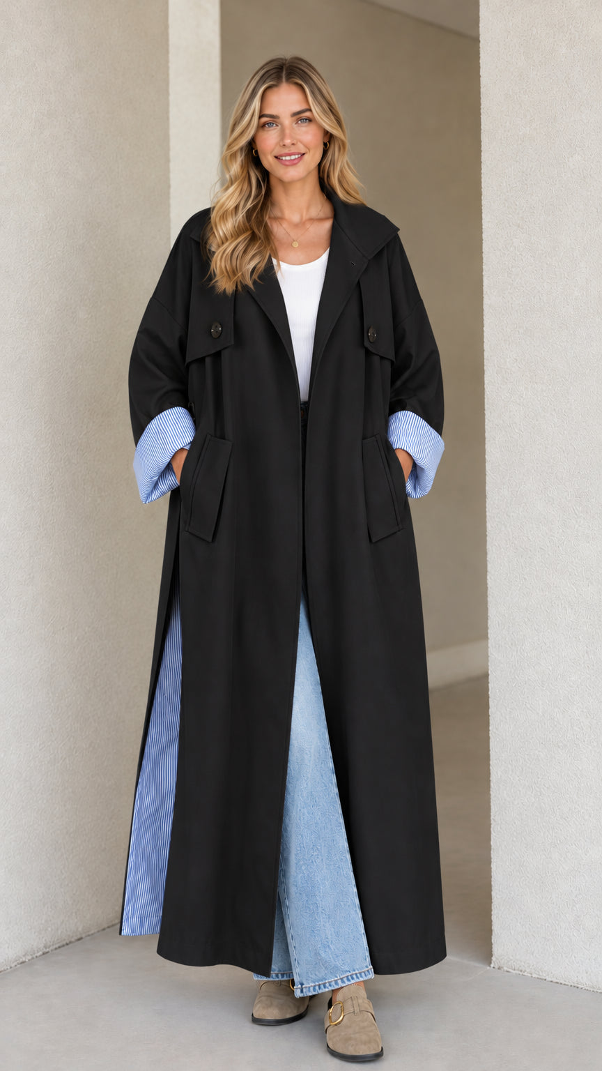 Front view of black maxi trench coat with blue striped cuff details