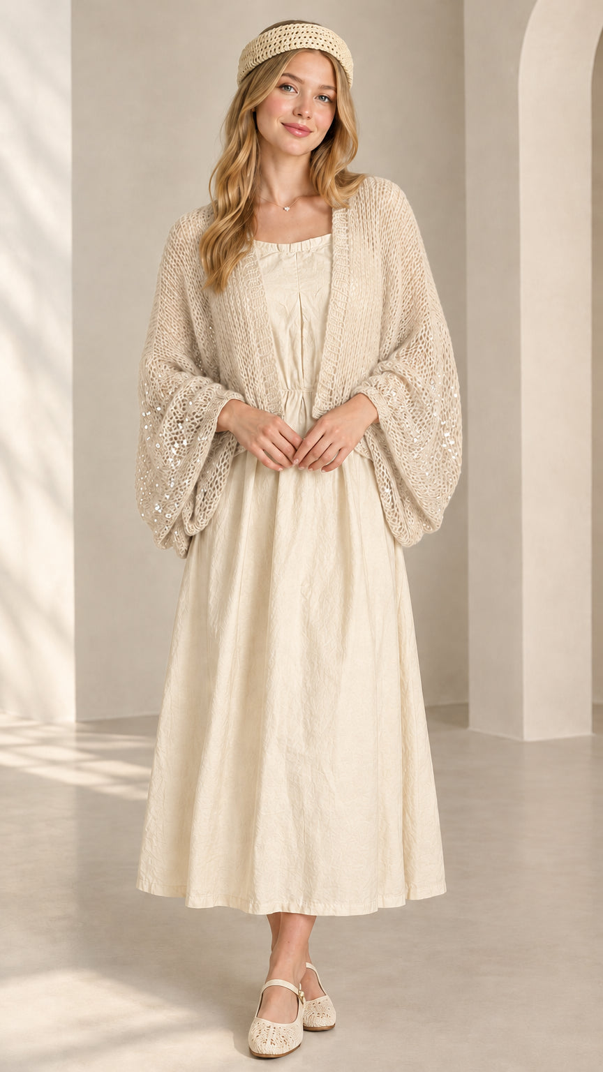 Front view of beige cream sequin open-knit shrug cardigan over cream dress