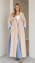 Front view of woman wearing beige maxi trench coat with striped cuff lining