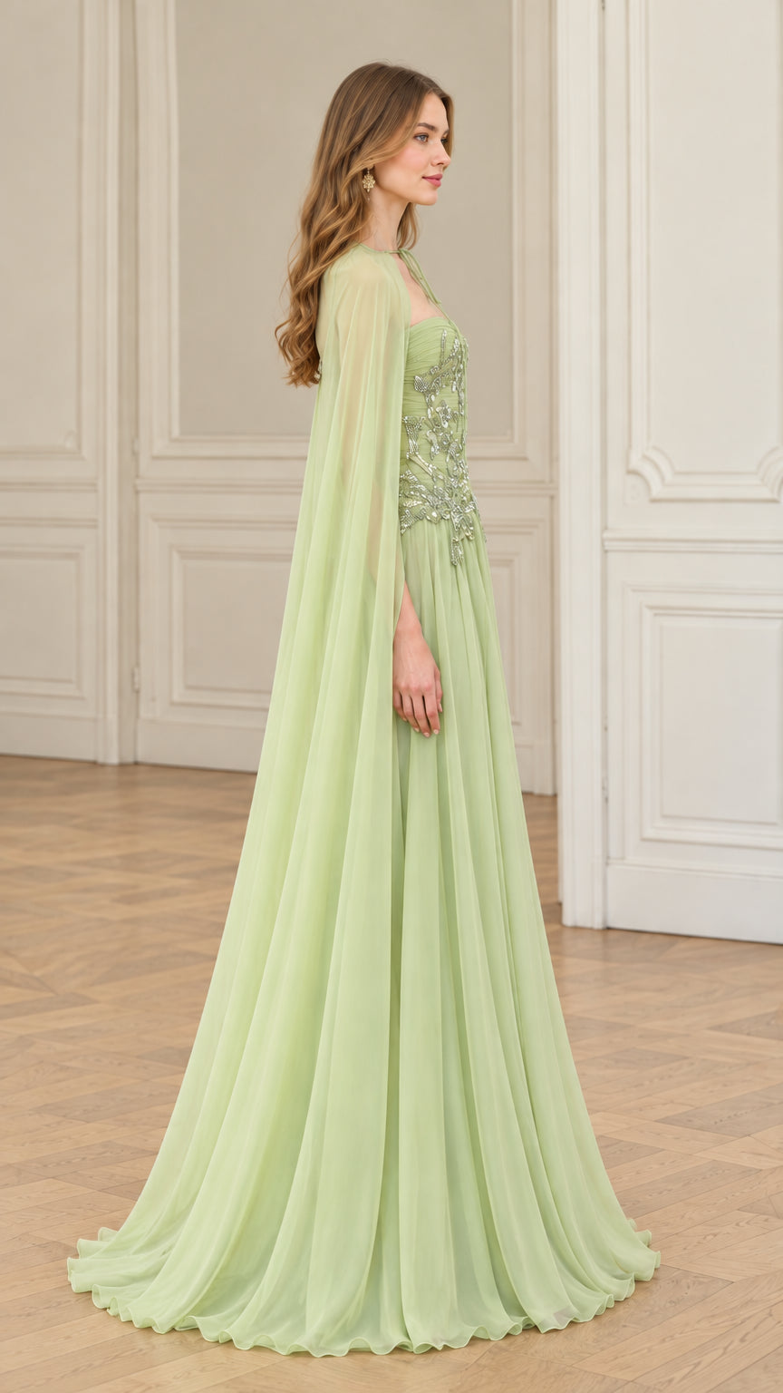 Side profile of sage green embellished formal gown with flowing floor-length cape