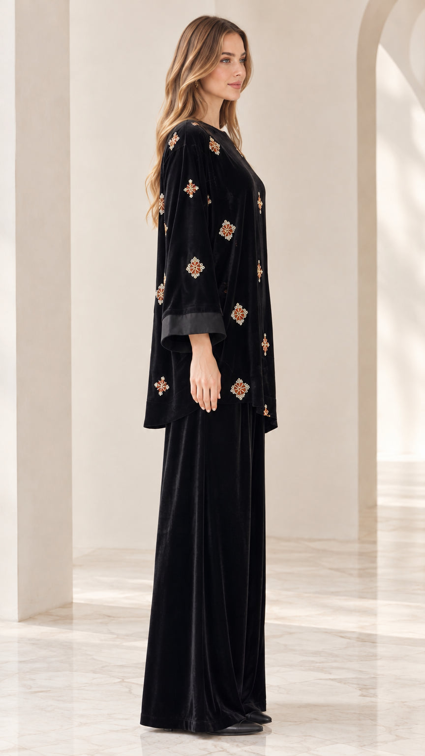 Side profile view of model wearing black velvet embroidered two piece outfit