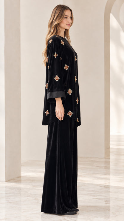 Side profile view of model wearing black velvet embroidered two piece outfit