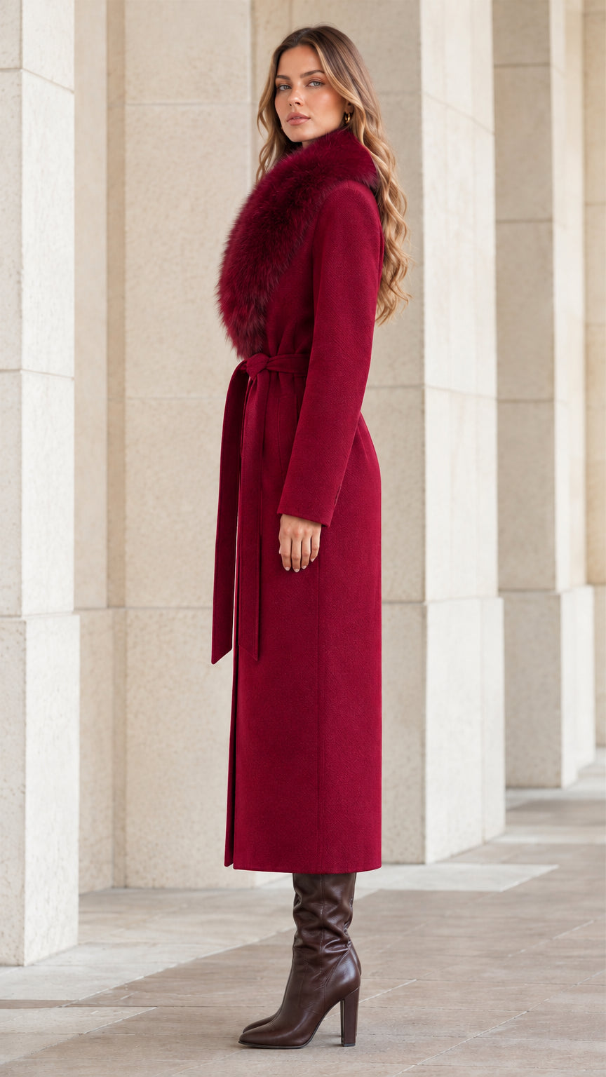 Side profile view of woman wearing burgundy long belted coat with faux fur trim