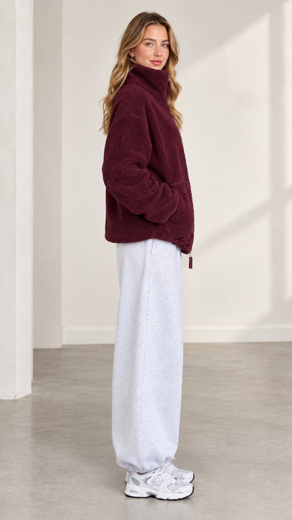 Side profile of model wearing burgundy plush fleece jacket with stand collar