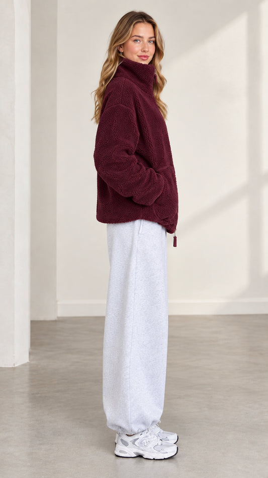 Side profile of model wearing burgundy plush fleece jacket with stand collar