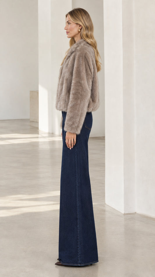 Side profile view of taupe cropped faux fur jacket paired with flare jeans