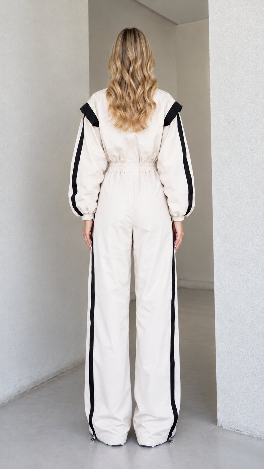 Back view of women's cream track jumpsuit showing elastic waist