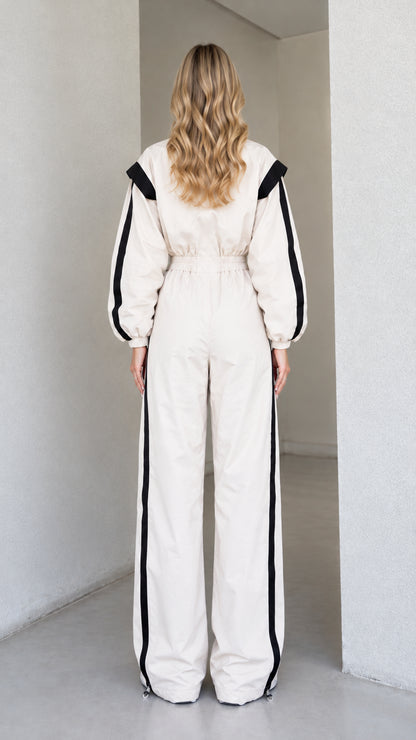 Back view of women's cream track jumpsuit showing elastic waist