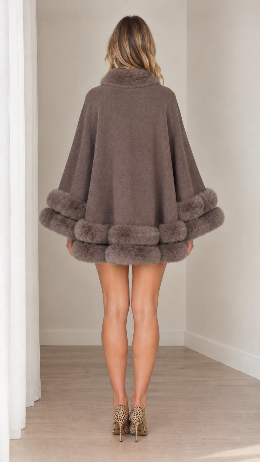 Back view of model showcasing the fluid drape of taupe faux fur cape