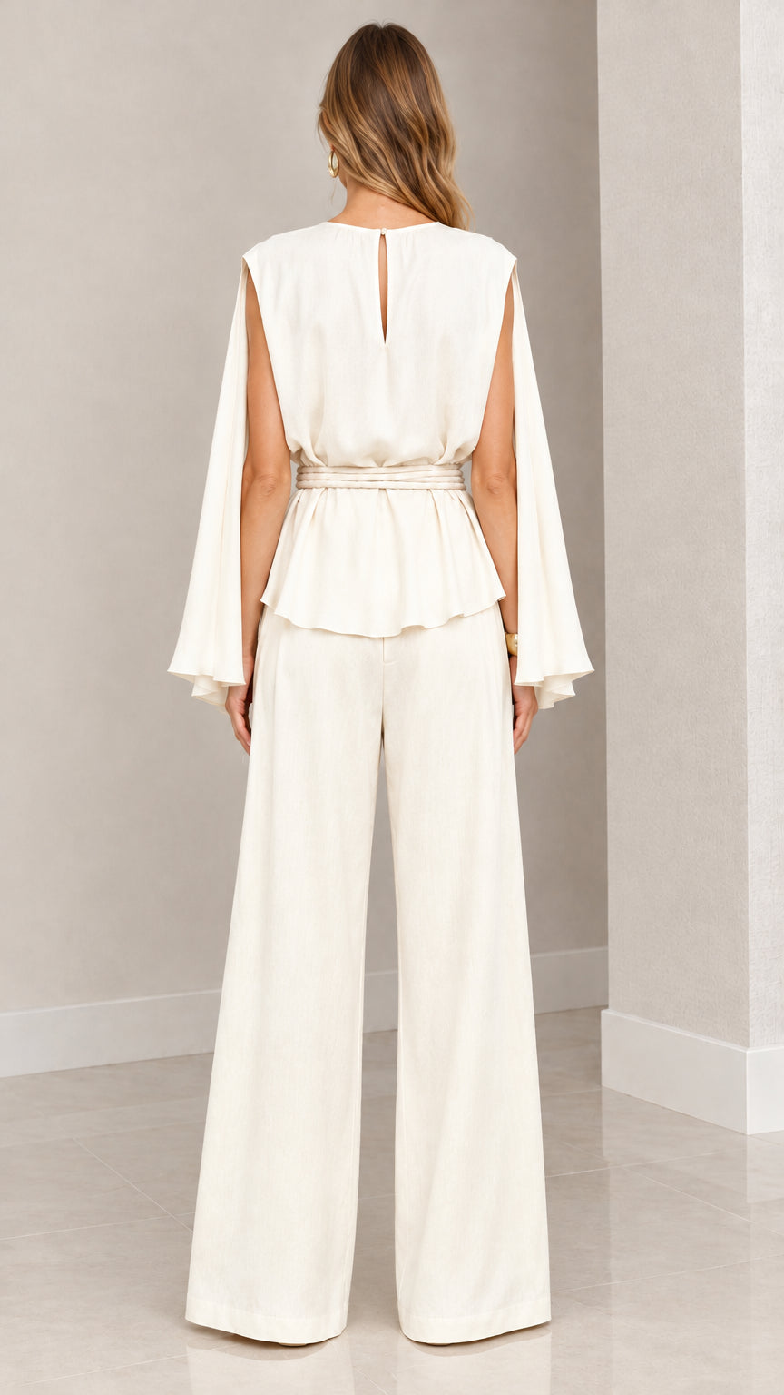 Back view of woman wearing cream cape top with keyhole back and wide leg trousers