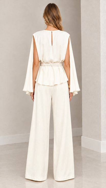 Back view of woman wearing cream cape top with keyhole back and wide leg trousers