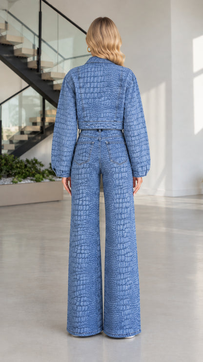 Back view of model wearing Denim Blue croc-textured denim cropped jacket and wide-leg trousers