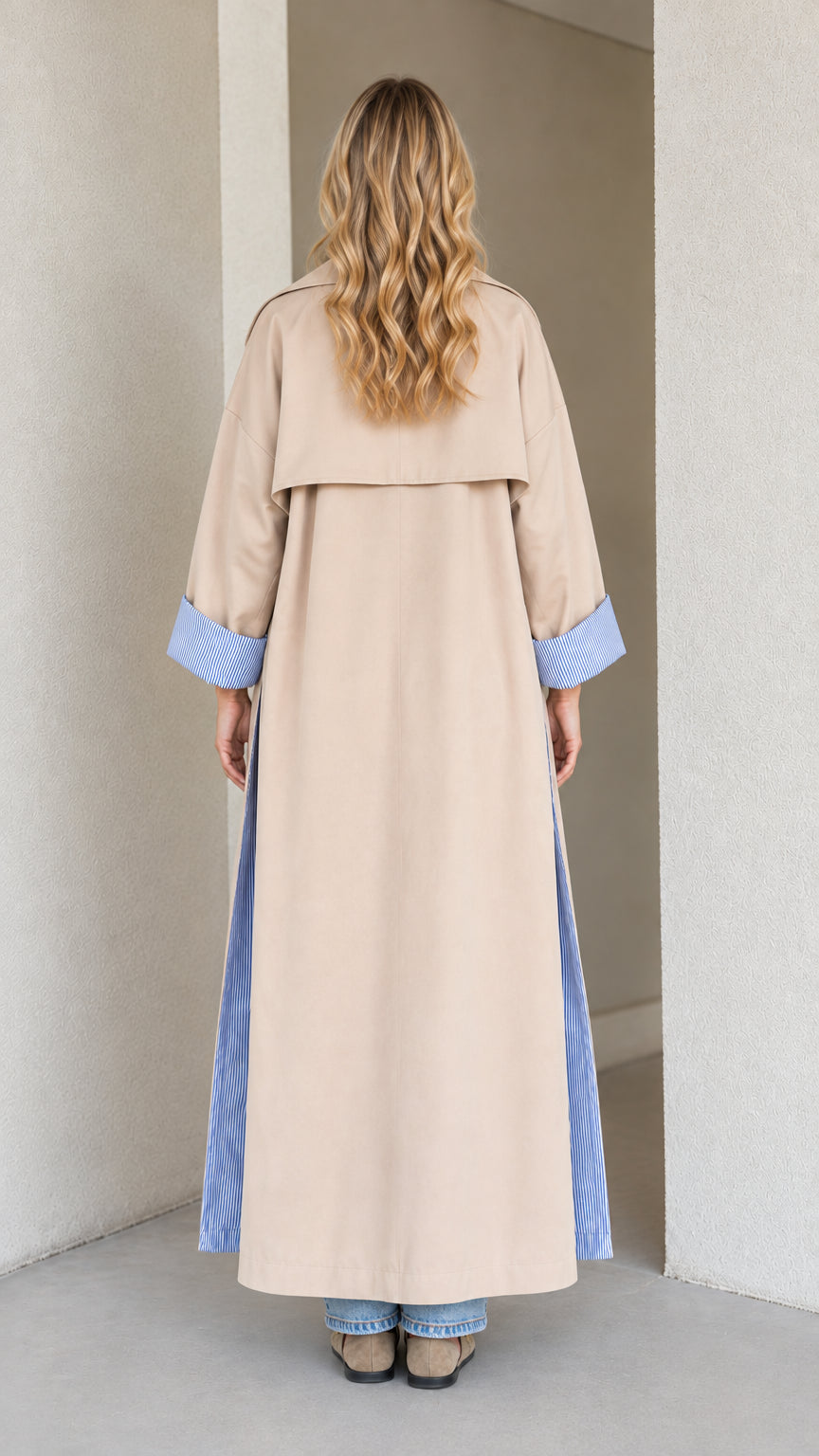 Back view of beige full-length trench coat with storm flap and split hem