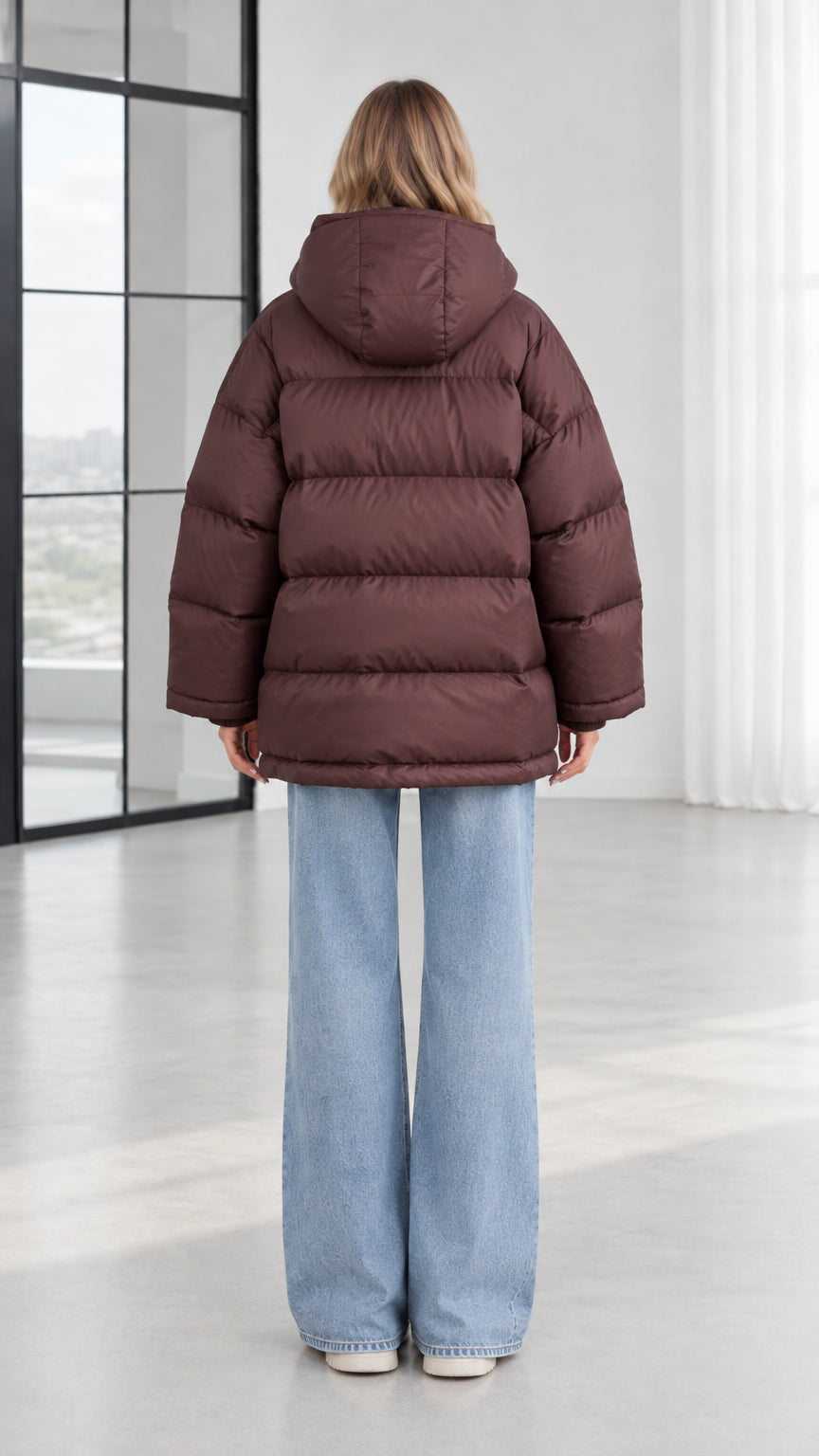 Back view of model showing horizontal quilting and hood on chocolate brown puffer jacket