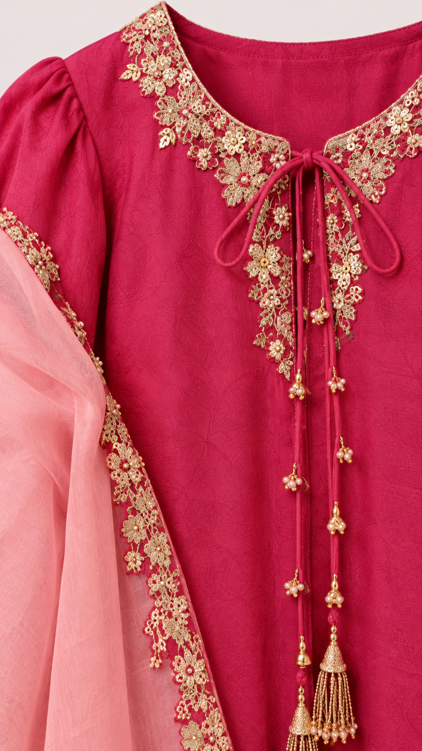 Close-up detail of gold floral embroidery and tassel ties on the neckline