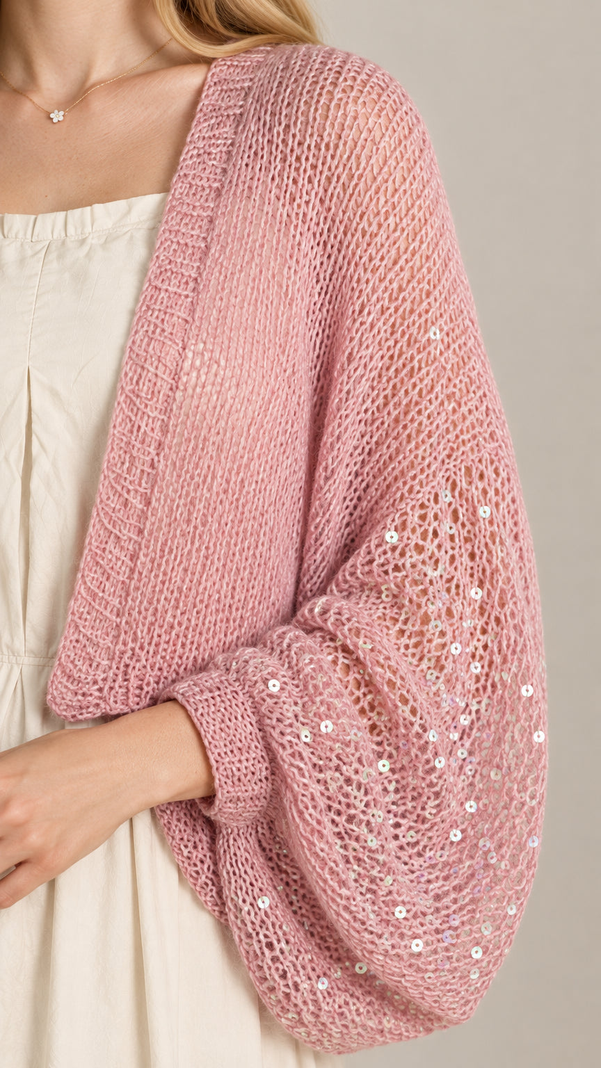 Close-up detail of pink open-knit fabric showing sequin embellishments and weave texture