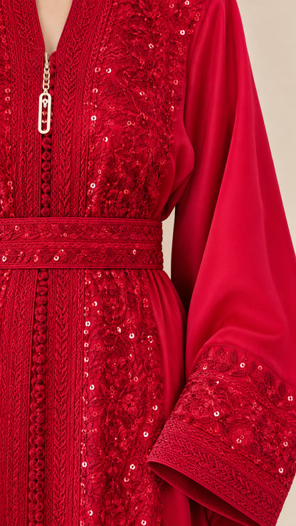 Close-up detail of red embroidery, sequin embellishment, belt, and neckline charm
