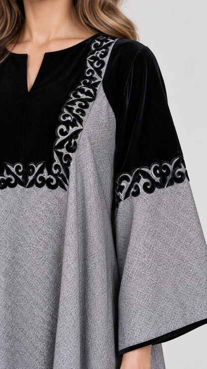 Close-up detail of black contrast panel with intricate scroll embroidery and notched neckline