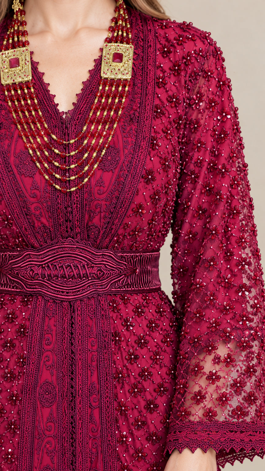 Close-up detail of ornate beading, V-neckline, and embroidered belt on magenta kaftan dress