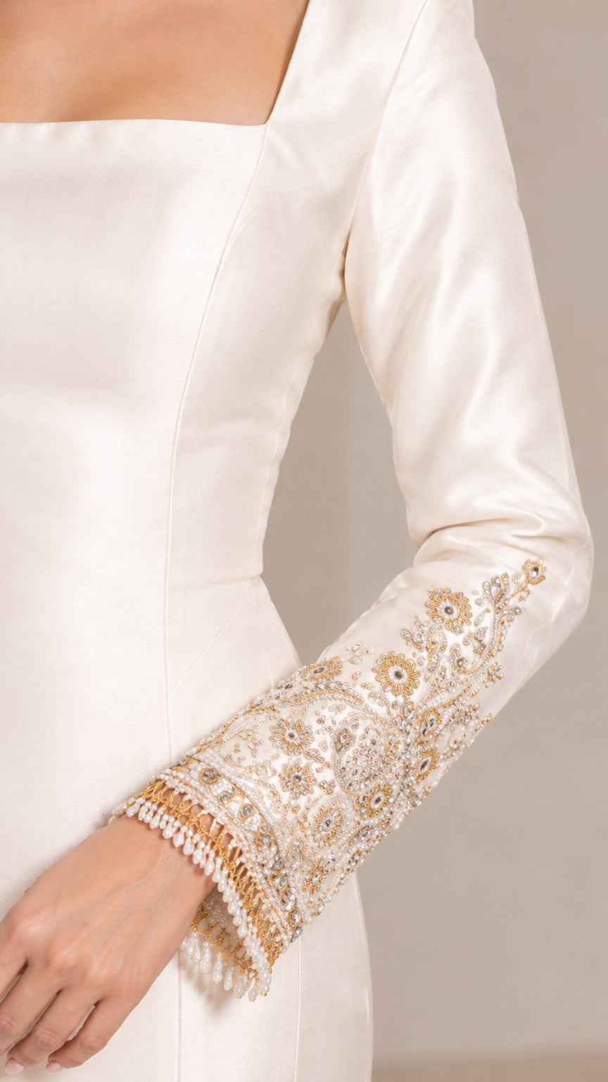 Close up of sleeve cuff featuring detailed gold embroidery, beadwork, and pearl fringe