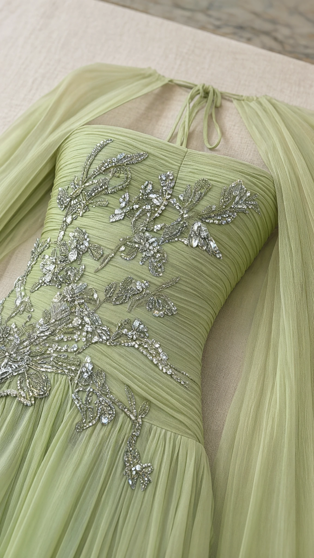 Close-up detail of silver floral beadwork and pleating on sage green gown bodice