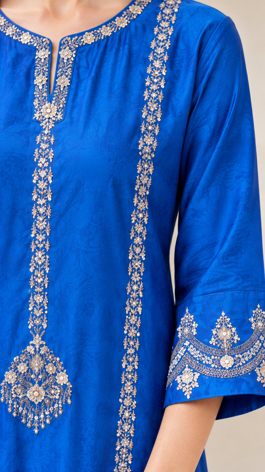 Close-up detail of ornate metallic embroidery on royal blue tunic neckline
