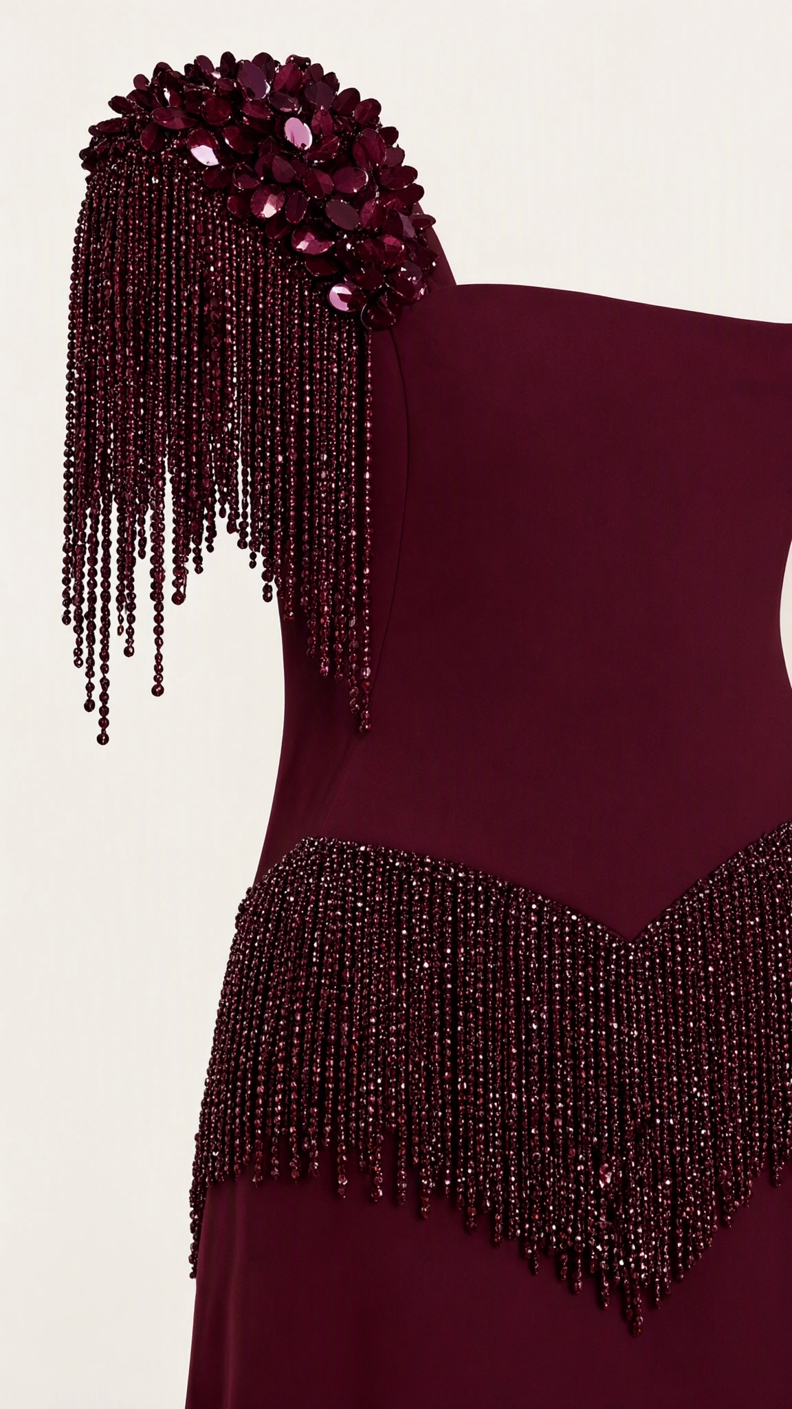Close-up detail of beaded fringe shoulder cap and chevron waist embellishment on burgundy gown