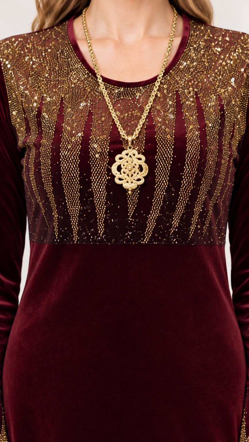 Close-up detail of glittering gold embellishment on the round neckline of burgundy velvet tunic