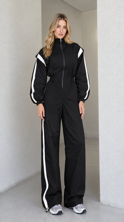 Full front view of women's black track jumpsuit with white side stripes