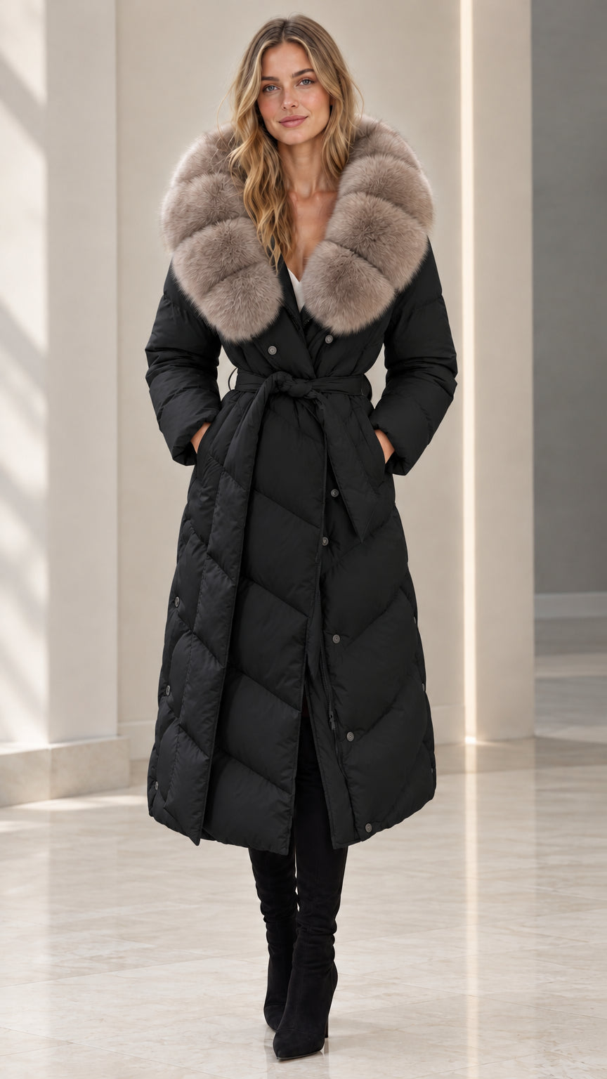 Front full-length view of woman wearing black belted maxi puffer coat with plush fur collar