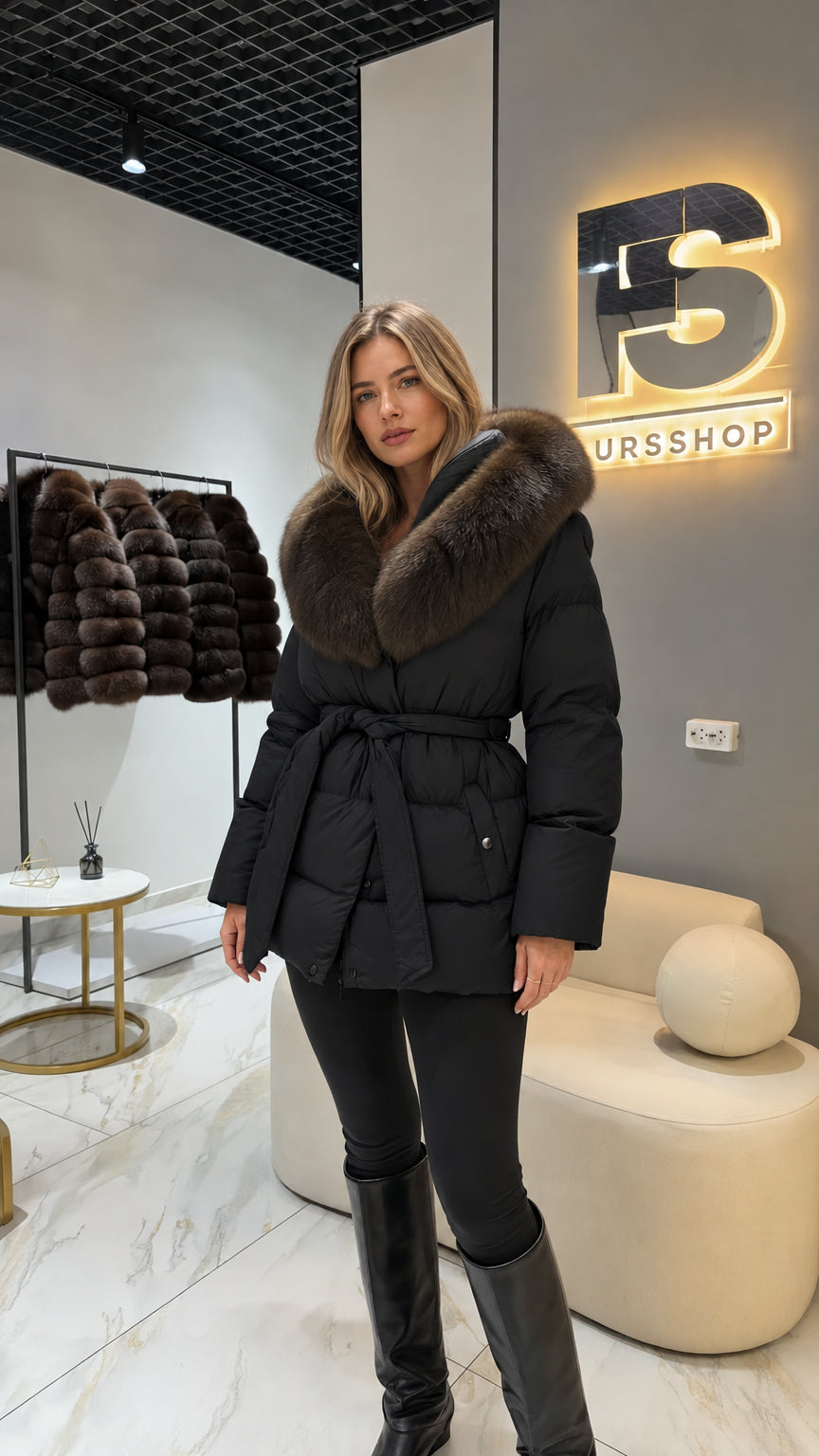 Model wearing black belted puffer coat with plush faux fur collar