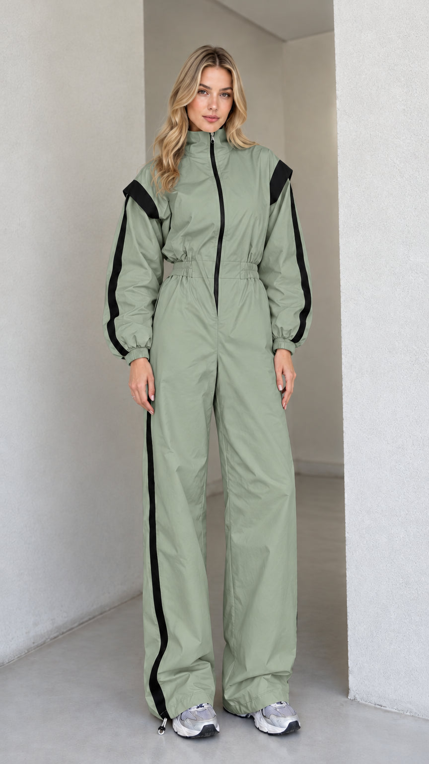 Full front view of women's sage green track jumpsuit with black side stripes